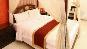 Ein Himmelsbett mit Baldachin, einem Holzkopfteil und einer roten Bettdecke.