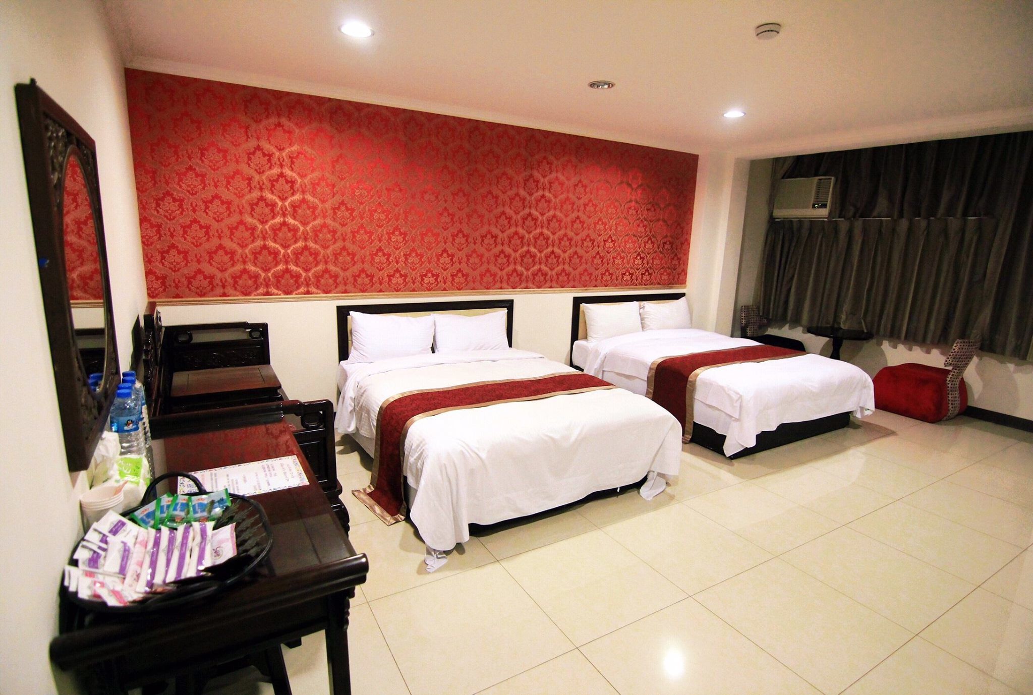 A hotel room with two beds, a desk, and a mirror.