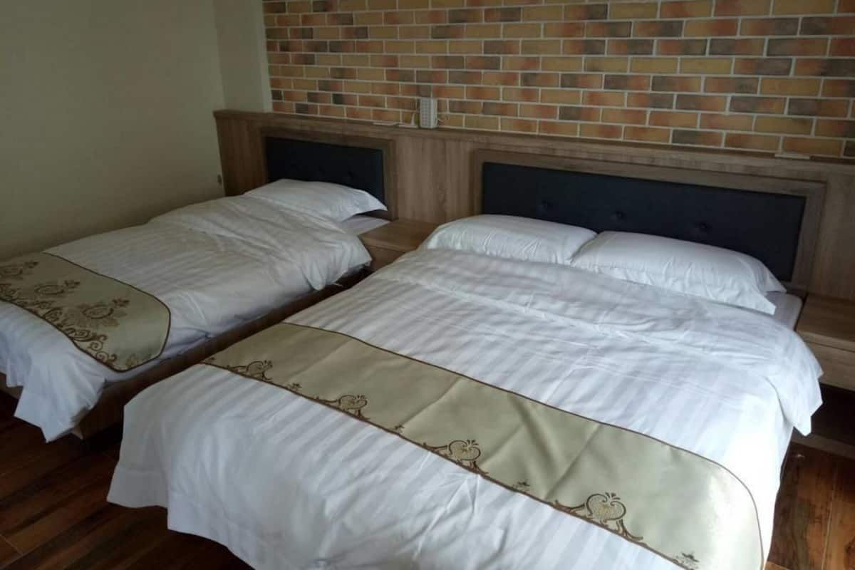 Two single beds with headboards, a brick wall, and a wooden floor.