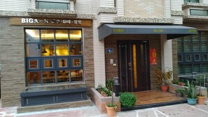 Un edificio con un escaparate que dice "BIG" y una puerta con un letrero encima.