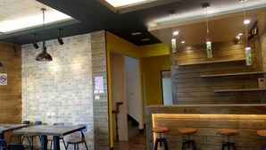 Un interior moderno con pared de ladrillo, detalles de madera y una zona de bar con taburetes.