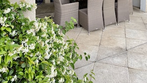 An outdoor patio with a brick fireplace, wicker furniture, and a tiled floor. - Big house with pool house, large garden in a marvelous vacation city (L'isle-Sur-La-Sorgue)