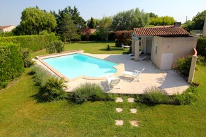 Enjoy a serene poolside retreat surrounded by lush greenery and a beautifully manicured lawn.
