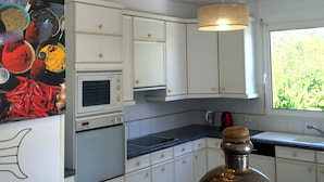 A modern kitchen with white cabinets, a stove, and a large decorative vase. - Big house with pool house, large garden in a marvelous vacation city (L'isle-Sur-La-Sorgue)