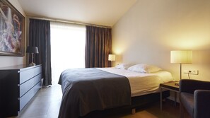 A hotel room with a bed, bedside table, lamp, chair, and a painting on the wall. - Apartment/ flat - Cadaques (Cadaques)