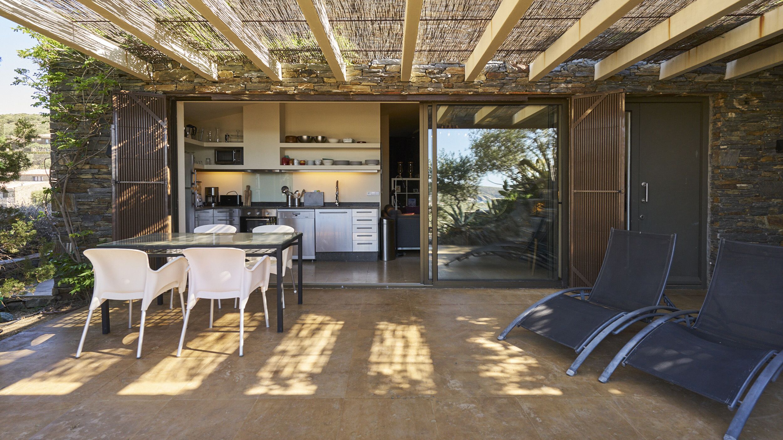 An open-plan kitchen with a dining area, a sliding glass door leading to a patio with outdoor seating.