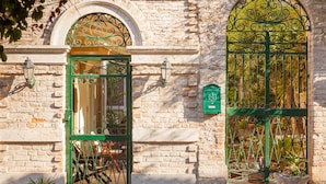 A stone building with a green metal gate and a green metal window frame.