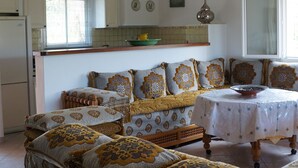 Ein gemütliches Wohnzimmer mit einer Sofagarnitur, einem Esstisch und einer Chandelier.