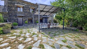Un bâtiment en pierre doté d’un patio couvert, d’un espace extérieur aménagé pour s’asseoir et de plantes en pot.