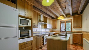 Une cuisine avec des meubles de rangement en bois, un four à micro-ondes encastré, une cuisinière et un évier.