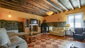 Un salon chaleureux avec un mur en pierre, une cheminée, un canapé et un téléviseur.