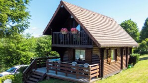 Une cabane en rondins dotée d’un balcon, d’une terrasse en bois et d’une petite piscine.