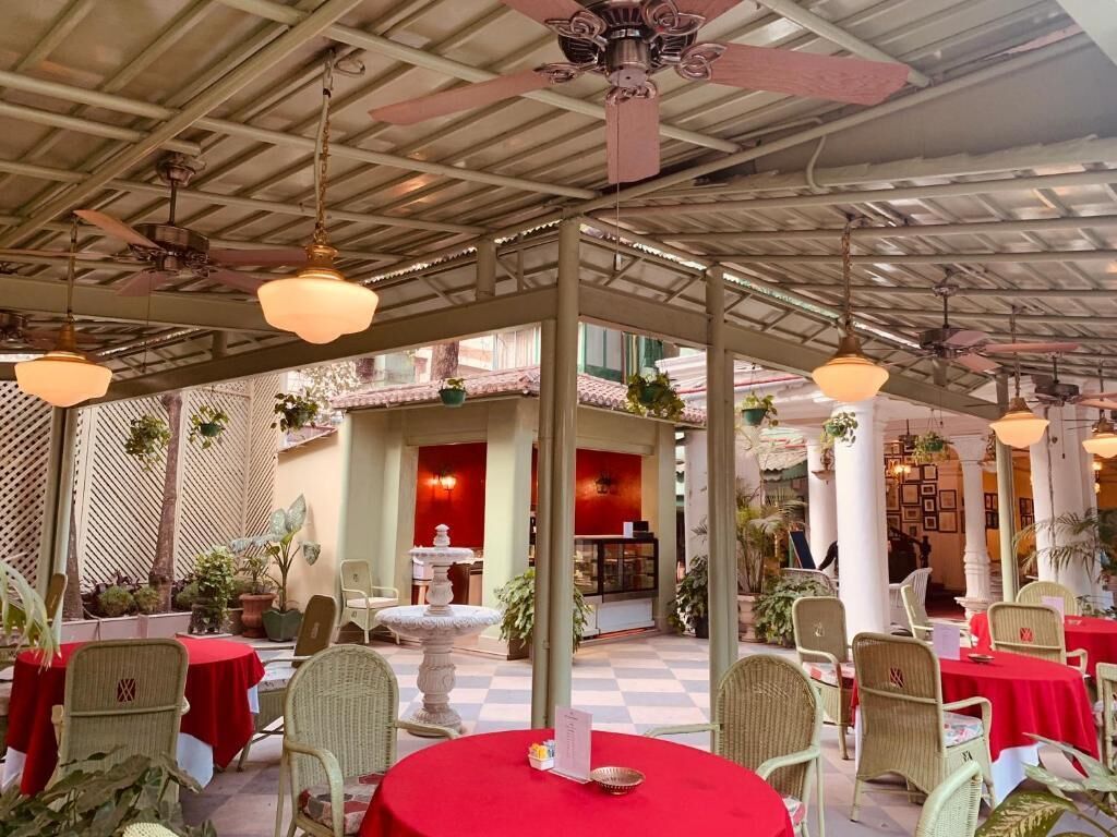 An indoor dining area with round tables, wicker chairs, and a checkered floor.
