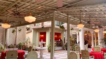An indoor dining area with round tables, wicker chairs, and a checkered floor.