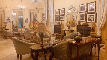 Un interior clásico con un conjunto de sofás, sillones, una araña y cuadros enmarcados en la pared.