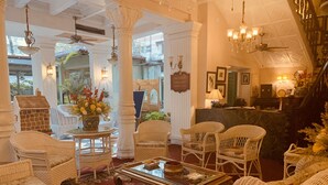 A spacious lobby with wicker furniture, a glass coffee table, and a reception desk.