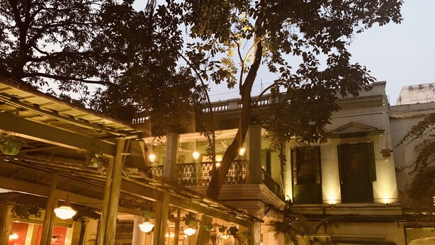 A traditional building with a balcony, potted plants, and hanging lights.