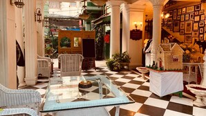 A hotel lobby with a checkered floor, wicker furniture, and a glass coffee table.
