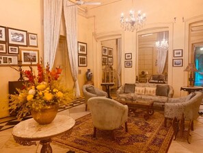 Un salon traditionnel comprenant un ensemble de canapés, des fauteuils, une table basse et un lustre.