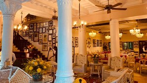 A spacious lobby with high ceilings, ornate columns, and chandeliers.