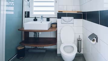 Et moderne badeværelse med en hvid vask, toilet og spejl.