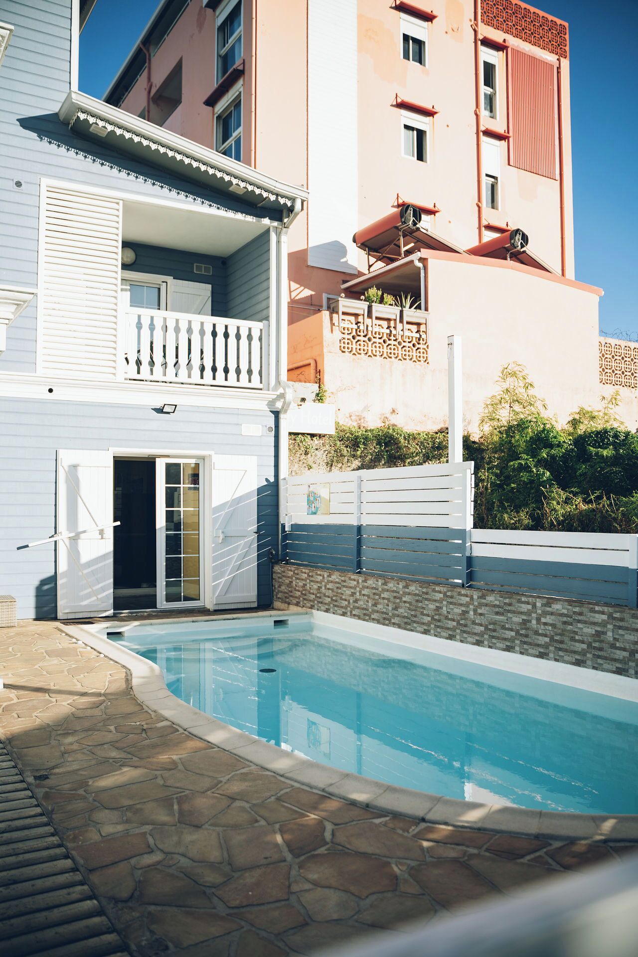Un edificio residencial con piscina, balcón y entrada protegida por un portón.