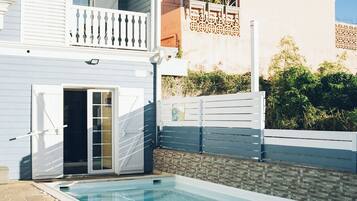 Un edificio residencial con piscina, balcón y entrada protegida por un portón.