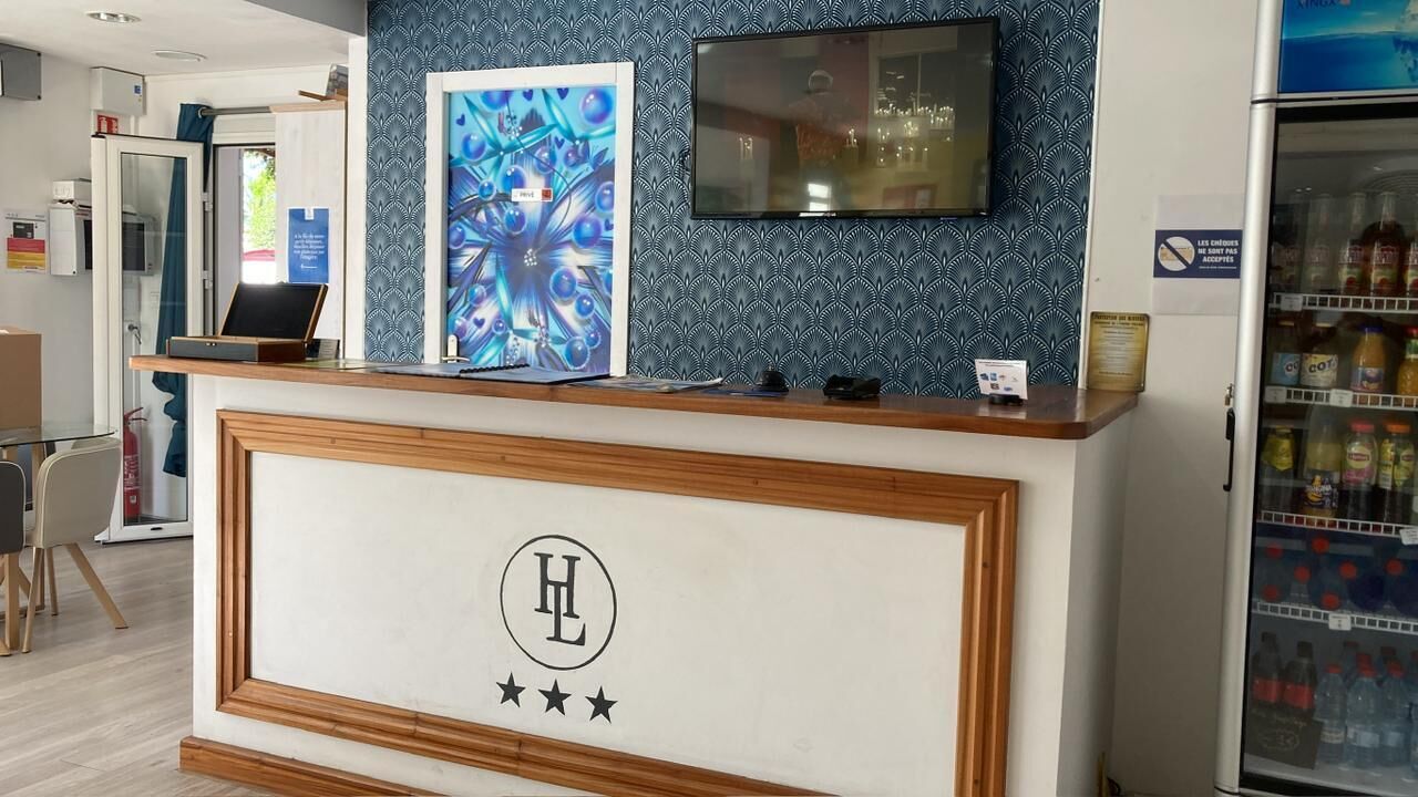 Una recepción de hotel con un logotipo, un televisor y un dispensador de bebidas.
