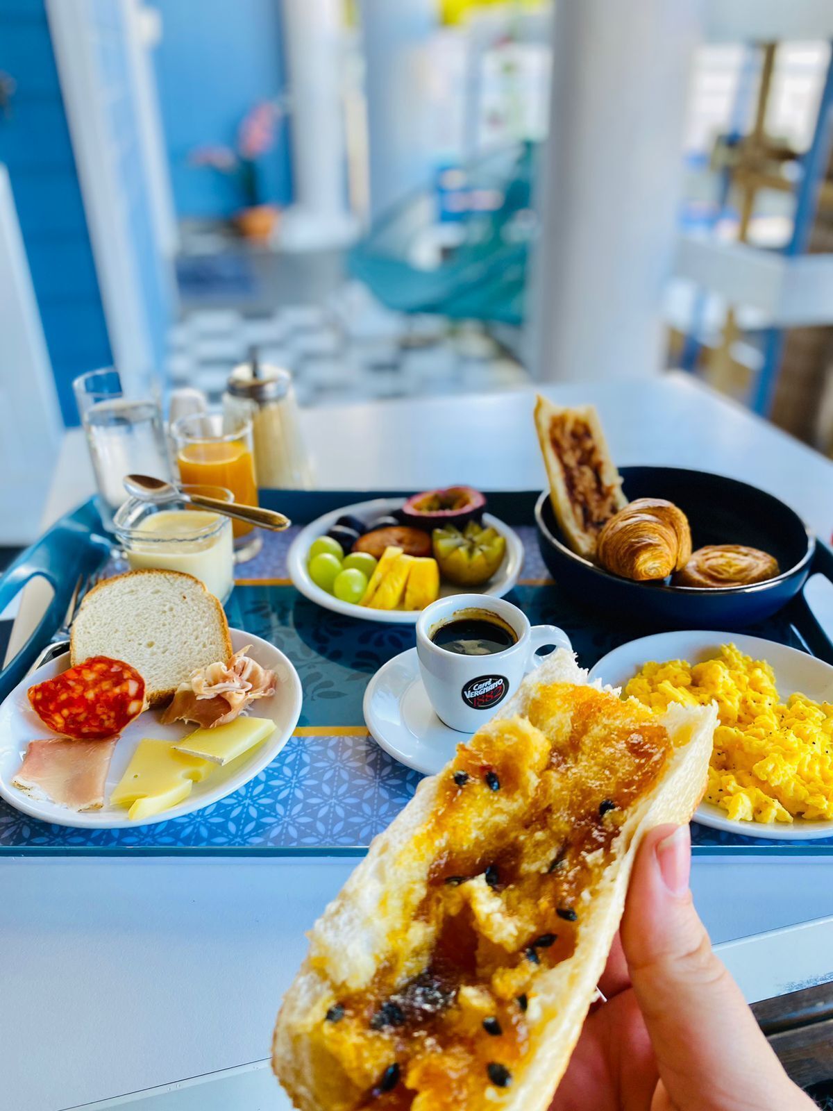 A breakfast tray with bread, cheese, ham, eggs, and fruit on a table.