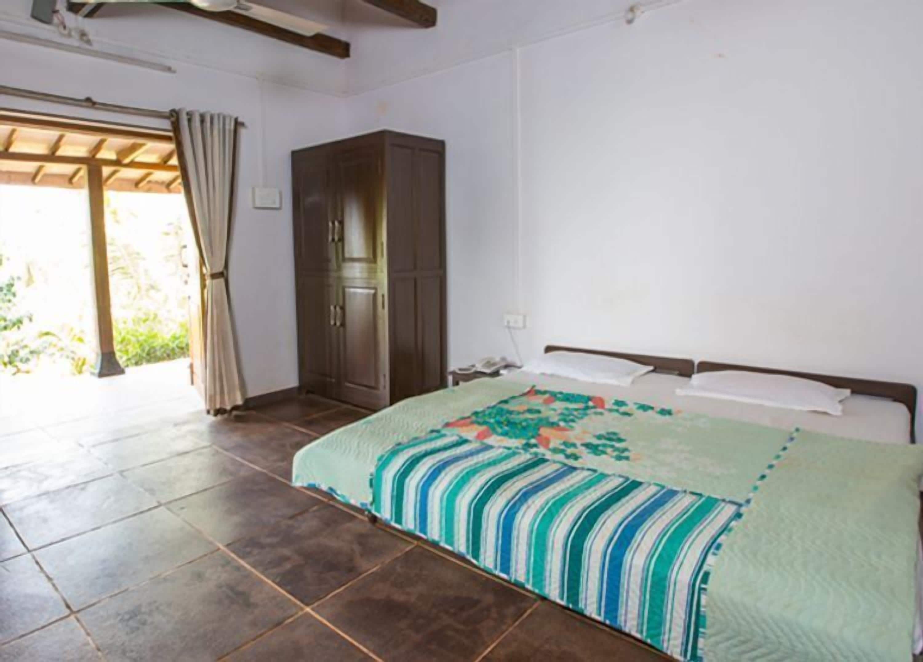 A bedroom with a bed, a wardrobe, and a door leading to an outdoor area.