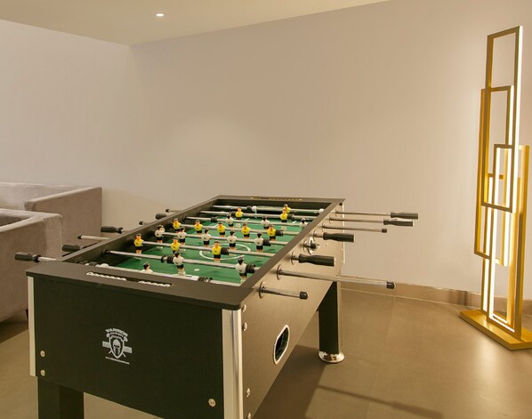 A foosball table in a room with a sofa and a decorative light fixture.