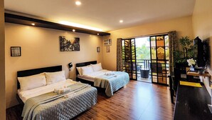 A hotel room with two beds, a large sliding glass door leading to a balcony, and a television on a stand. - A&A Garden Suites (Amadeo)