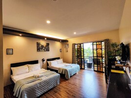 Una habitación de hotel con dos camas, un amplio ventanal corredero que da a un balcón y un televisor sobre un soporte.