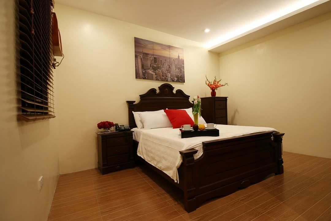 Una camera da letto ordinata con un letto di legno, un comodino, un condizionatore d'aria a muro e un quadro con una veduta cittadina.