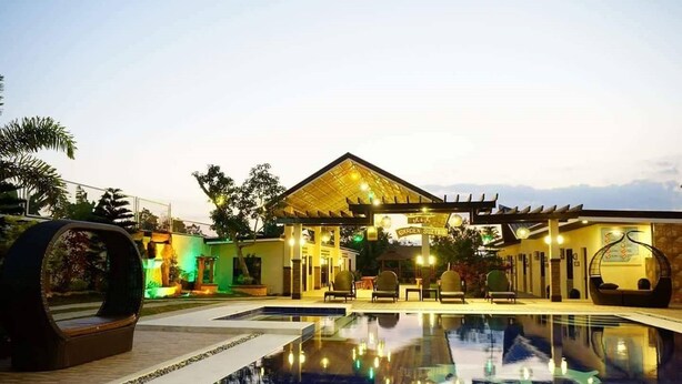 A hotel with a pool, outdoor seating, and a covered area with a sign reading "Garden Suites". - A&A Garden Suites (Amadeo)