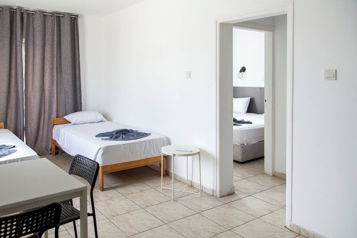 Una habitación con dos camas, una mesita y una silla.