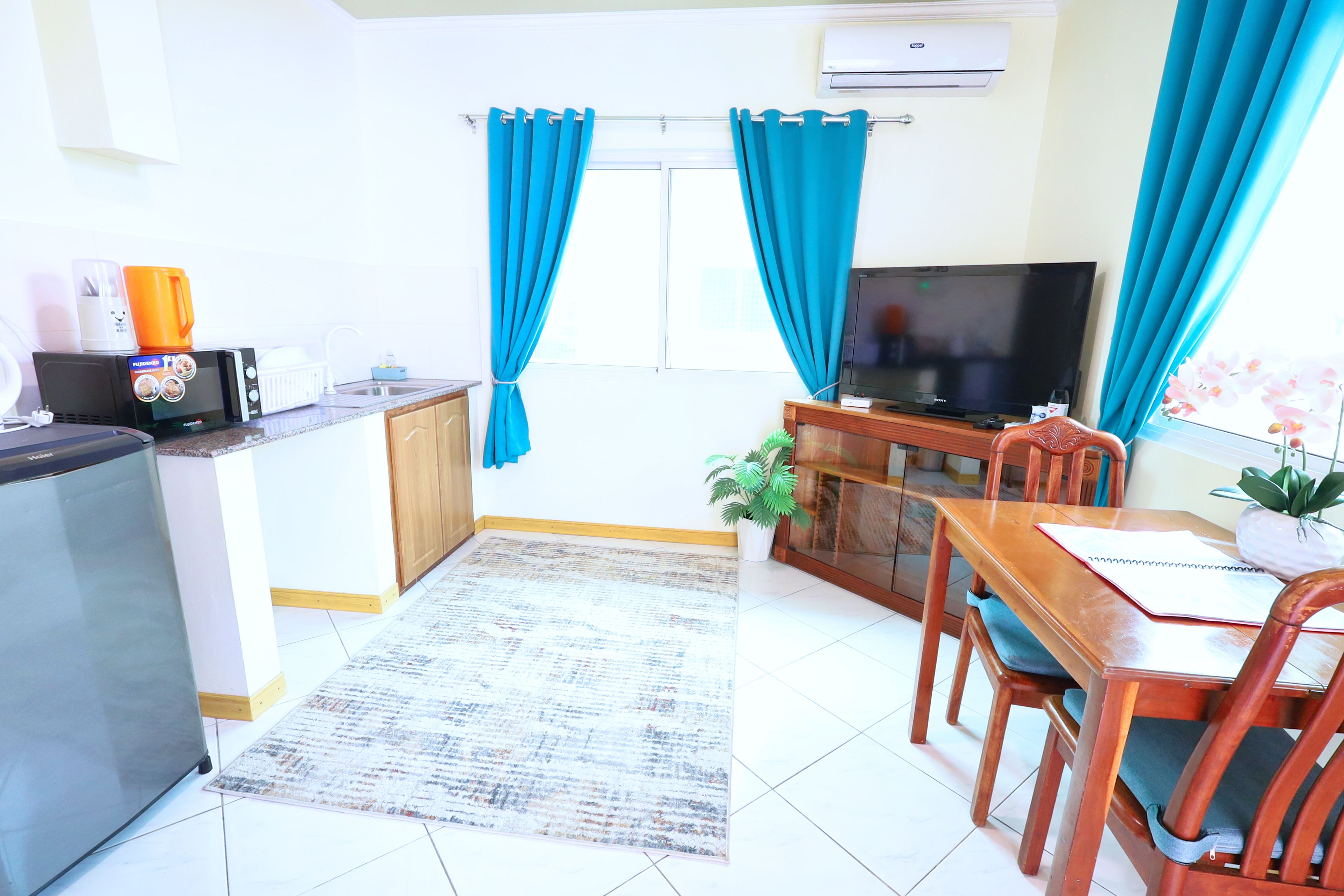 Un espacio habitable compacto con kitchenette, comedor y sala de estar con televisor.
