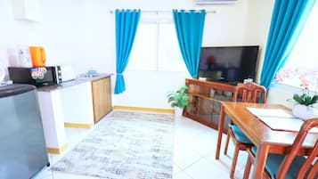 Un espacio habitable compacto con kitchenette, comedor y sala de estar con televisor.