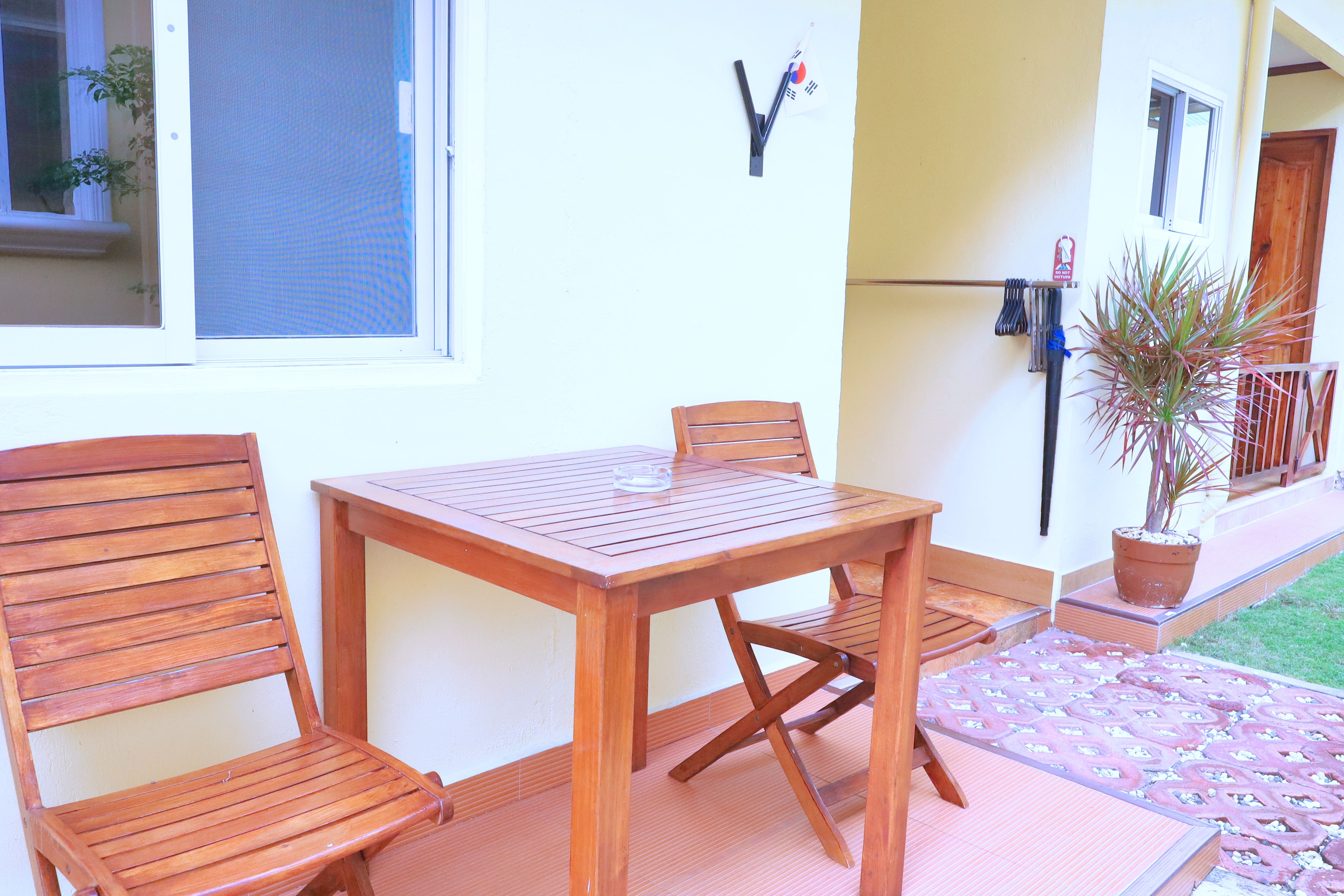 A wooden table and chairs set against a white wall, with a window and a door visible in the background.