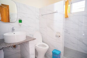 A bathroom with a white sink, toilet, and a shower area. - Alona Austria Resort (Panglao)