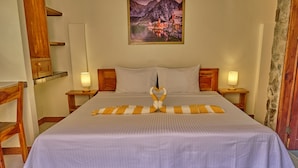 A neatly made bed with a heart-shaped pillow arrangement, wooden headboards, and bedside lamps. - Alona Austria Resort (Panglao)