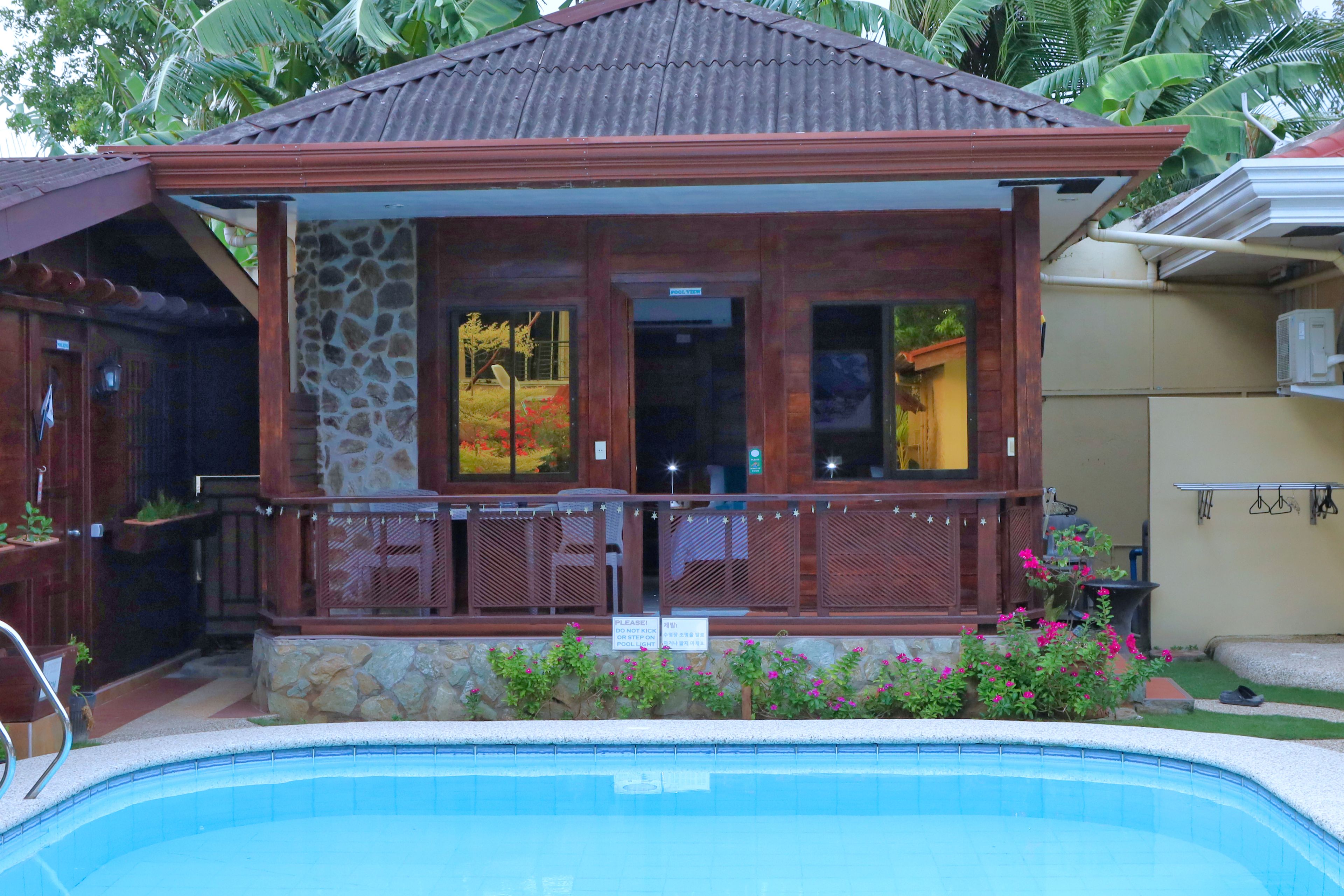 Ein Gebäude am Pool mit einer Steinaußenfassade, großen Fenstern und einer überdachten Terrasse.