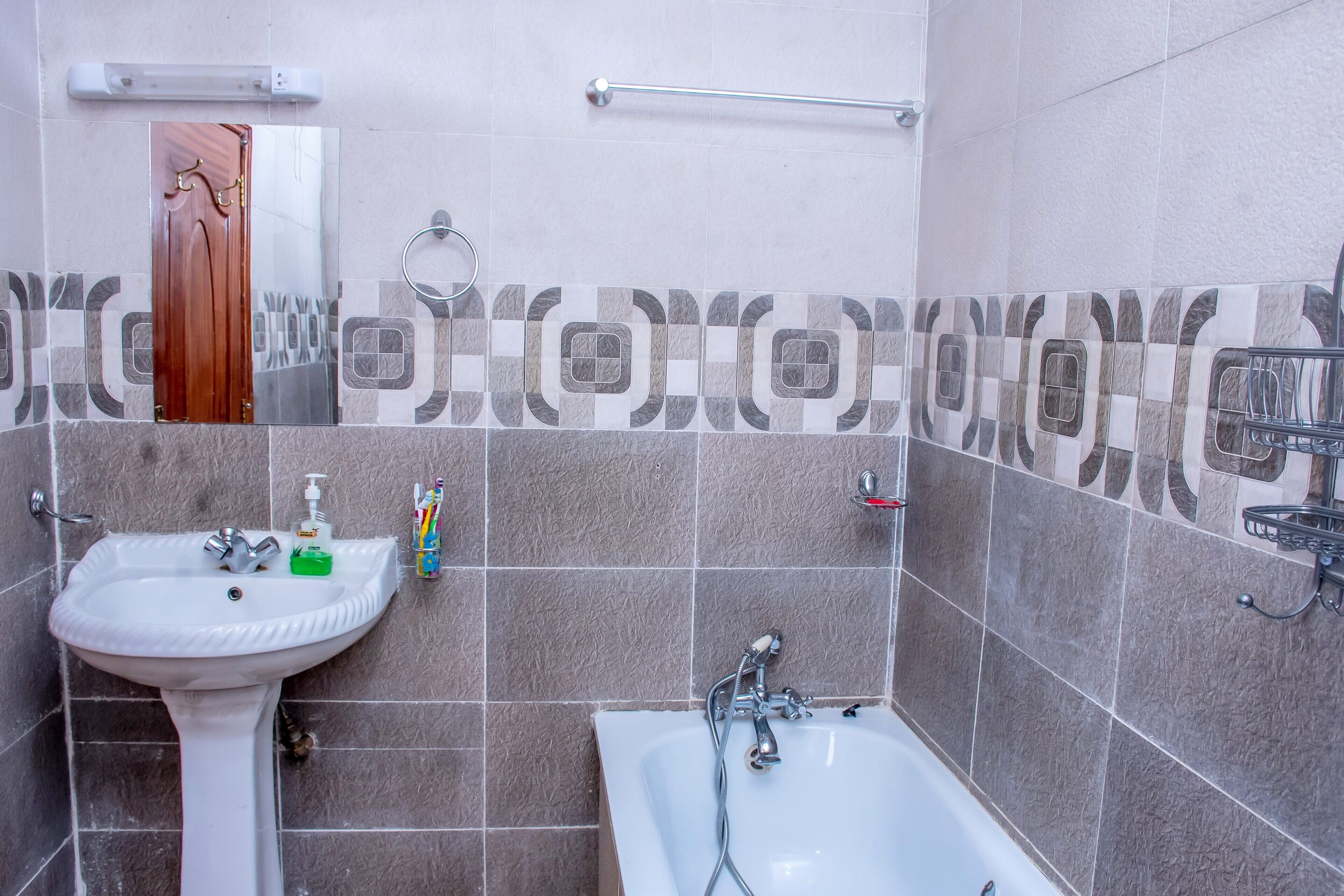 A bathroom with a sink, mirror, and bathtub.