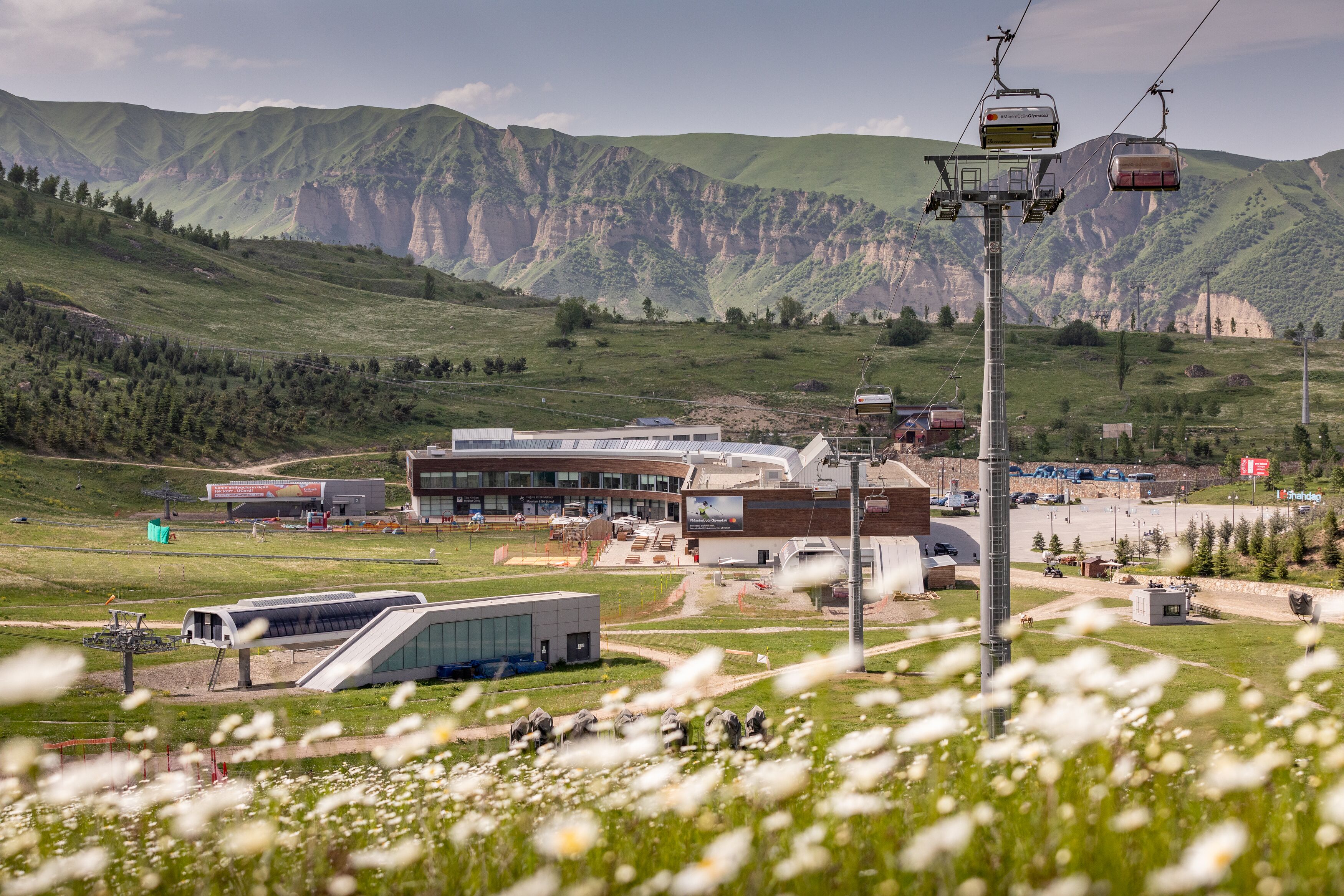 A modern building with a glass facade, surrounded by a mountainous landscape and a ski lift.
