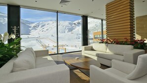 Un salon moderne doté d’une grande fenêtre donnant sur un paysage montagneux enneigé.