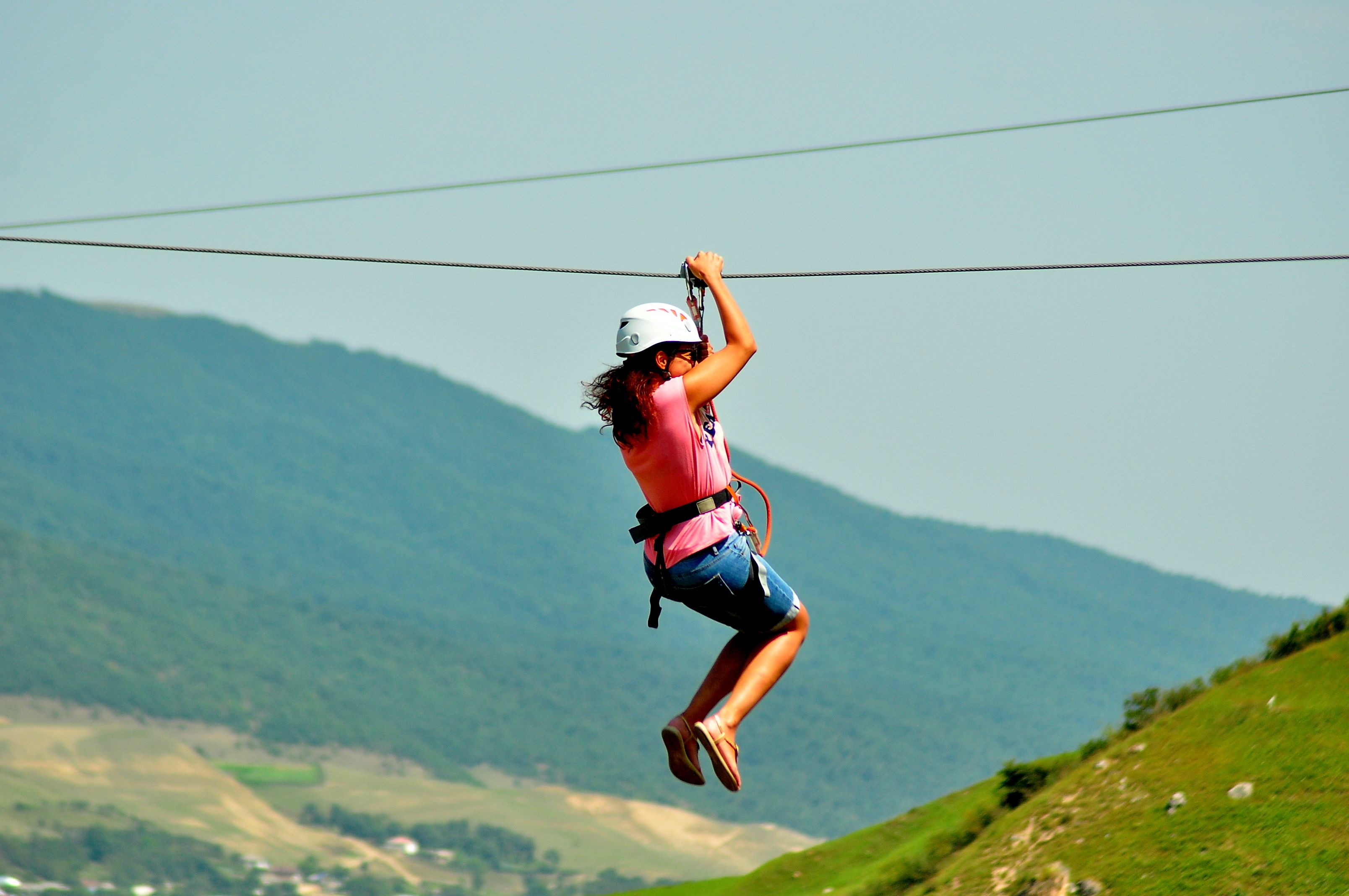 A person zip-lining over a mountainous landscape.