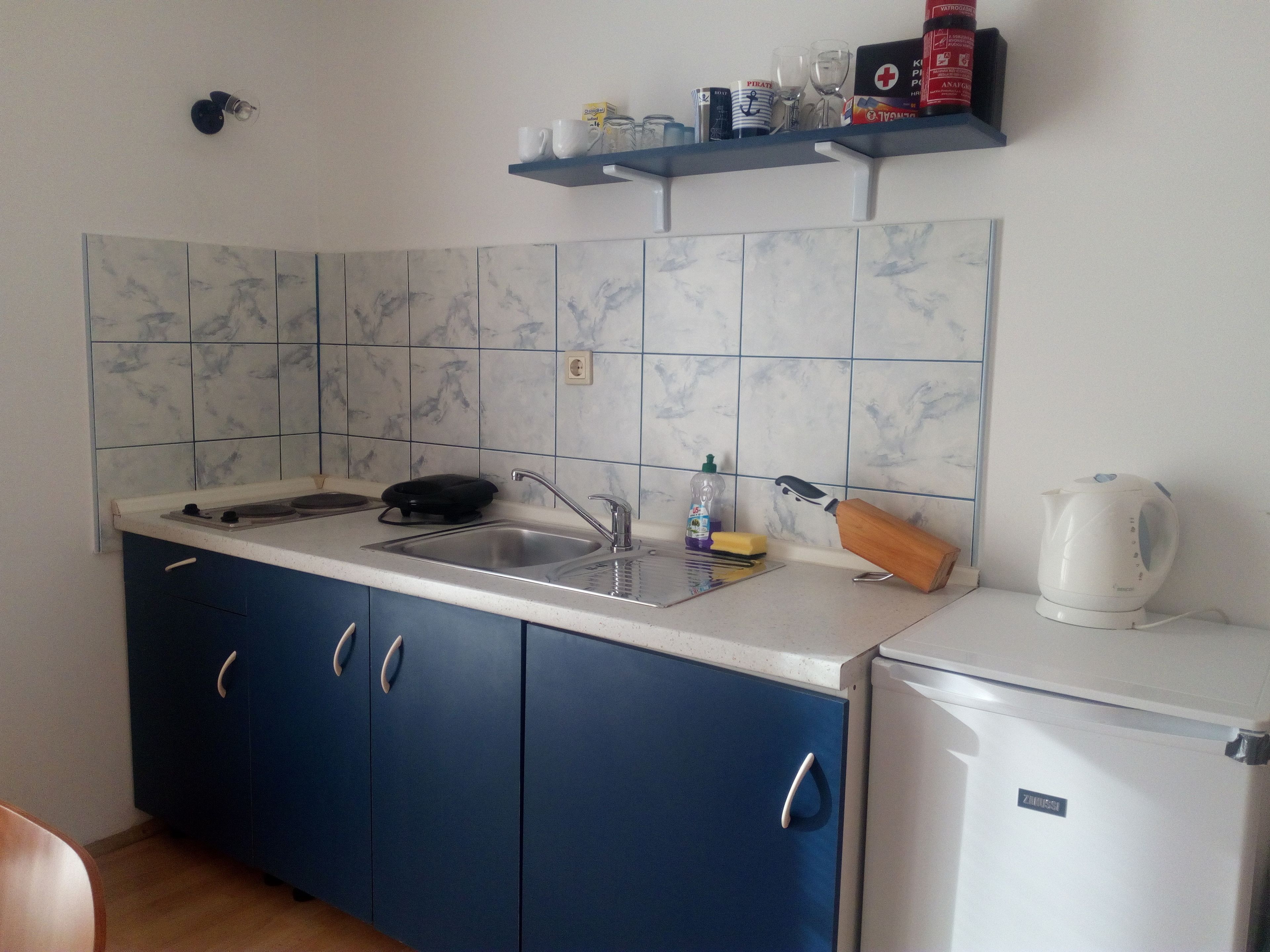 A compact kitchen with a sink, stove, and a small refrigerator.