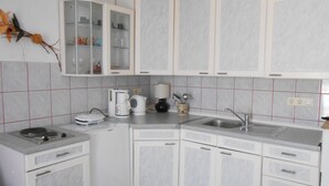 Une cuisine moderne avec des armoires blanches, un four encastré, un évier et une machine à café.