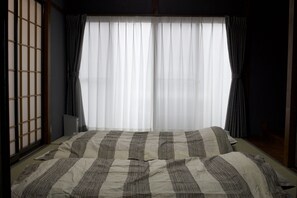 A bedroom with a large bed, a shoji screen, and a view of the outside through sheer curtains. - Lee106 Iida Accomodation (Iida)