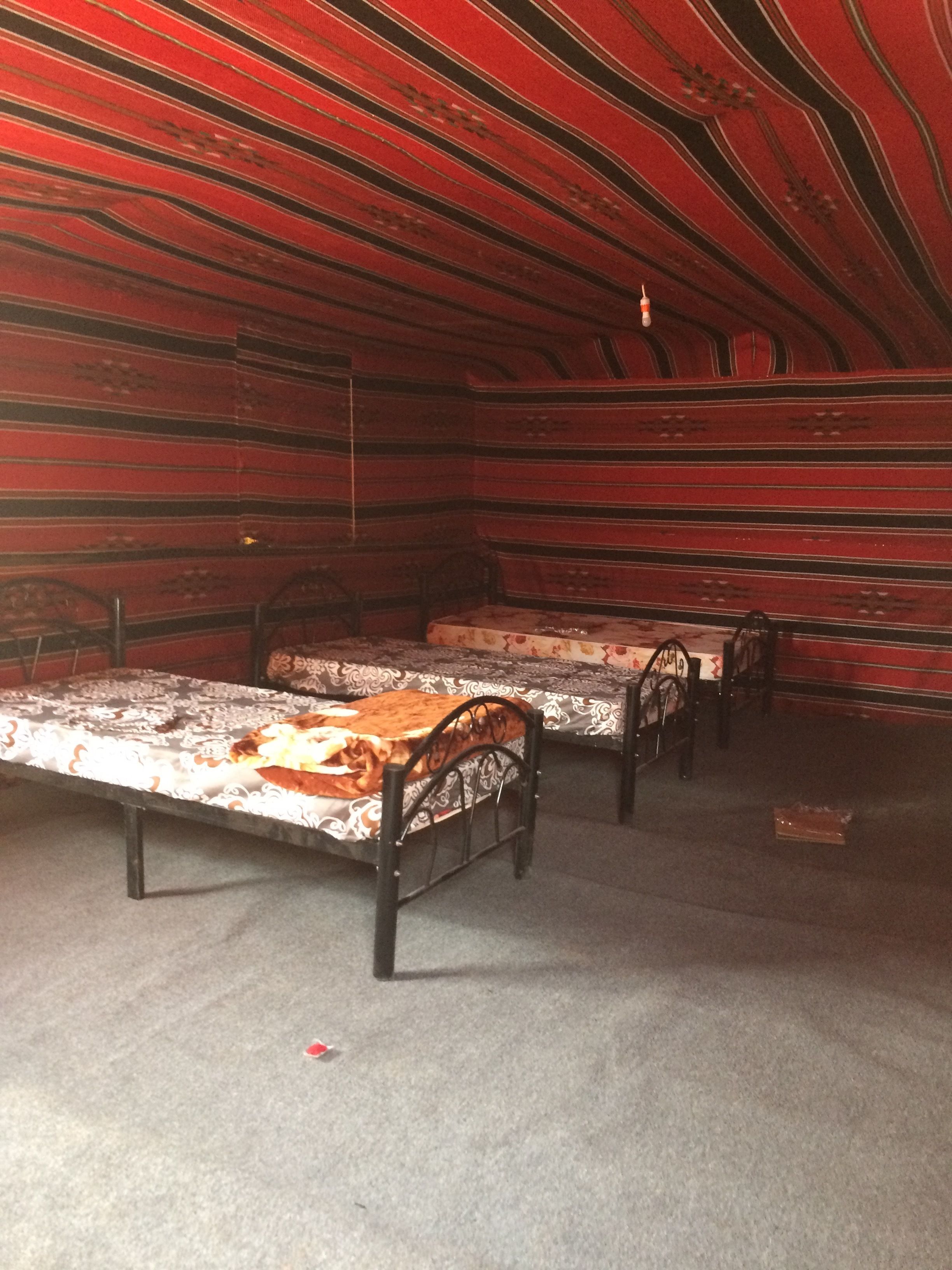 Una habitación con dos camas, piso alfombrado y techo rojo con estampado.